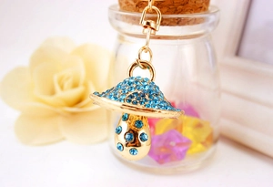 Detail of mushroom keychain with blue rhinestones and gold metal finish for handbags