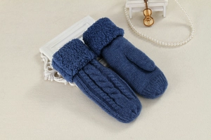 Detailed view of blue cable knit mittens with plush faux fur cuffs on beige background