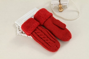 Close-up of red knitted mittens with fuzzy faux fur cuffs on a textured surface