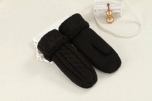 Close-up of black cable knit mittens featuring plush fur cuffs and decorative props
