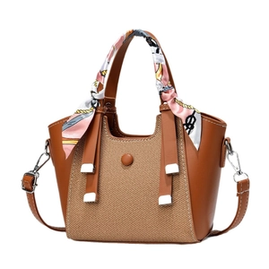 Brown leather and woven tote bag with a floral silk scarf wrapped around the handle