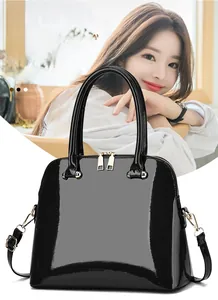 Close-up of high-gloss black patent leather handbag featuring reinforced handles and metal zipper