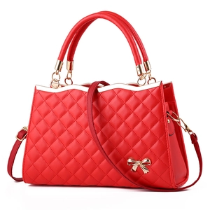 Detailaufnahme der roten gesteppten Handtasche mit goldener Schleife und Nahtstruktur