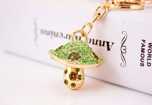 Close-up of golden mushroom keychain with sparkling green rhinestones on metal