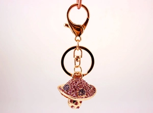 Macro shot of a golden mushroom keychain with sparkling pink and purple rhinestones