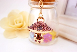 Detailed view of mushroom keychain with purple rhinestones on a warm floral background