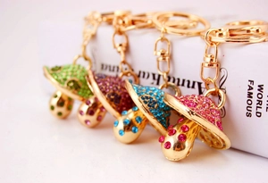 Detail of four colorful rhinestone mushroom keychains with lobster clasps on a book