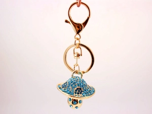 Macro shot of gold-tone mushroom keychain with shimmering blue rhinestones and lobster clasp