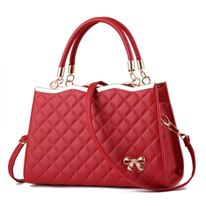 Detailansicht der roten gesteppten Handtasche mit goldener Schleife und gewelltem Rand