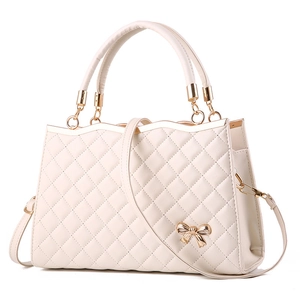 Detailansicht der cremeweißen Stepptasche mit goldener Schleifenschnalle und Lederstruktur