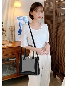 Polished black dome bag with gold hardware details and an adjustable shoulder strap