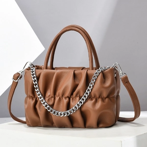 Brown ruched cloud handbag with silver metal chain and adjustable strap on white pedestal
