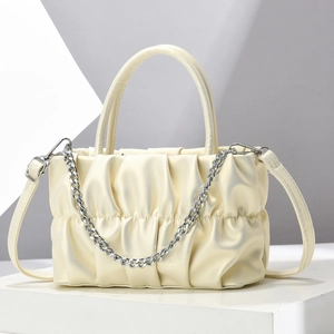 Close-up of cream pleated shoulder bag with silver chain detail and leather texture