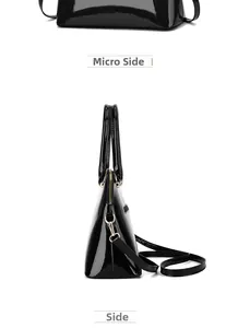 Detail view of glossy black shell handbag featuring gold zipper and removable shoulder strap