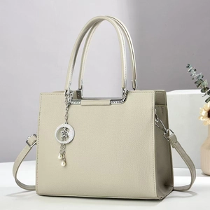 Gros plan du sac en cuir beige avec pendentif étoile argenté et détails en perles