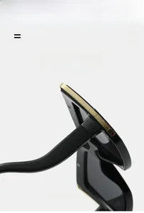 Close-up of black oversized sunglasses with gold metal trim and textured temples
