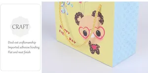 Dettaglio della borsa regalo in carta con orso cartone e manici in corda intrecciata