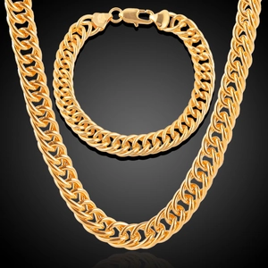 Detailed close-up of 18K gold plated thick curb chain necklace and bracelet set on black background