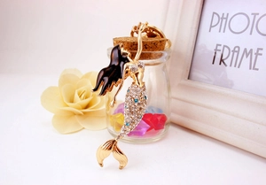 Detail view of gold mermaid keychain with black enamel hair and sparkling blue crystals