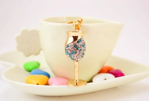 Detail of crystal wine glass keychain with blue rhinestones on a ceramic cup