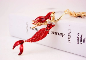 Detail of mermaid keychain with red rhinestones and golden hardware on a white book