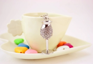 Macro shot of a silver rhinestone wine glass keychain hanging on a yellow ceramic cup