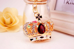 Close-up of golden crown keychain with red drop gemstone and white rhinestones