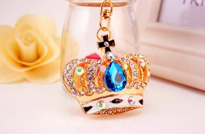 Detailed close-up of golden crown keychain featuring blue teardrop crystal and rhinestones