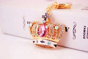 Detail of golden alloy crown keychain featuring pink teardrop gemstone and crystals