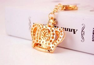 Close-up of golden crown keychain with crystal rhinestones on a white book surface