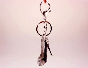 Close-up of a silver keychain with a black high heel pendant featuring sparkling rhinestones
