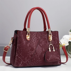 Detailed close-up of wine red snakeskin texture handbag with gold metal hardware and purse