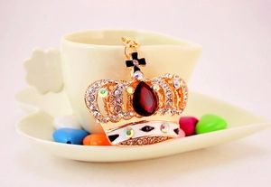 Macro shot of gold crown keychain with large red crystal and multi-color rhinestones