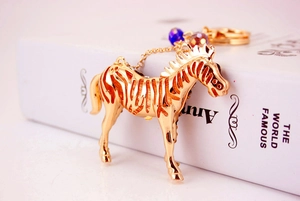 Detailed close-up of a golden zebra keychain with intricate hollow patterns and beads