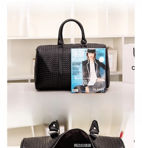 Détail d'un grand sac de voyage tressé noir avec espace pour 3-4 manteaux et poche latérale