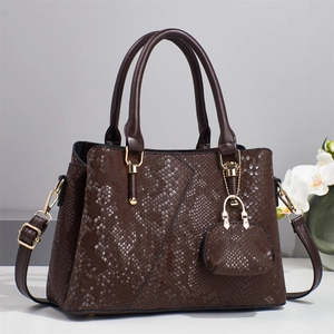 Close-up of brown snake texture tote bag with gold hardware and mini charm accessory