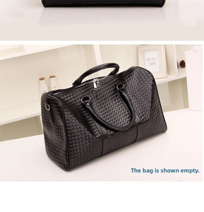 Détail du sac de voyage noir tissé avec poignées renforcées et finitions métalliques