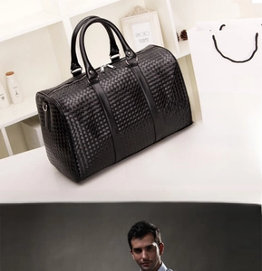 Détail de la texture tressée noire d'un grand sac de voyage avec poignées et anneaux en D