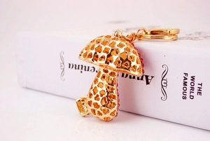 Detail of a golden mushroom keychain with pink crystals on an open book background