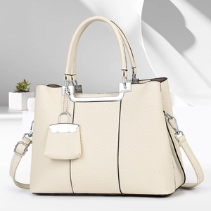 Close-up of cream lychee-textured leather handbag with silver hardware and charms