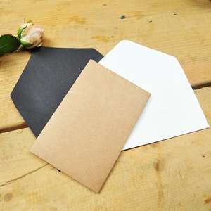 Mini vintage kraft paper card envelopes in black, white and tan on wooden surface