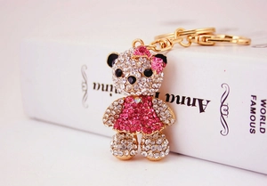 Close-up of a teddy bear keychain with pink and silver rhinestones on an open book