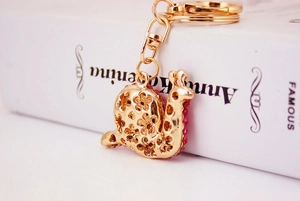 Macro shot of gold snail keychain with pink rhinestones and floral hollow pattern