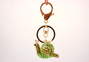 Detailed view of the cute snail keychain with green rhinestones and golden metal hardware