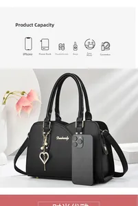 Detail of black pebbled leather handbag with gold metal logo and pearl heart charm