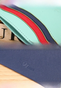 Detail of cross-grain leather card holder with contrast stripes and precise stitching