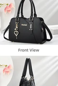 Detail of black lychee grain leather handbag with gold logo and heart pearl pendant