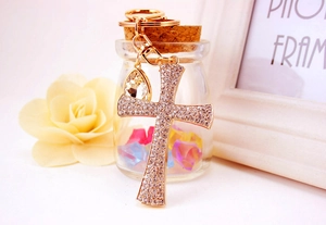 Close-up of golden cross keychain with rhinestones and teardrop crystal pendant