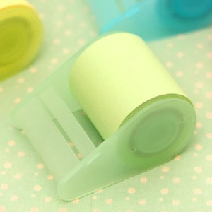 Green adhesive sticky note roll with tape dispenser on a light green polka dot background