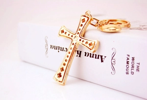 Close-up of golden cross keychain with heart charm on a vintage book backdrop